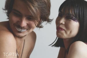 Fun, creative portrait of a couple smiling with glitter makeup, expressing joy and style. Photo by Tia Haygood.