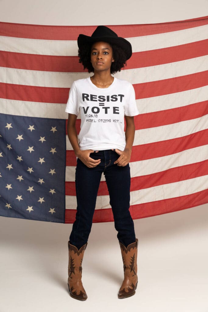A portrait of a black woman in a shirt against racism, standing ahead of a country's flag - Tokyo Portrait Photographer