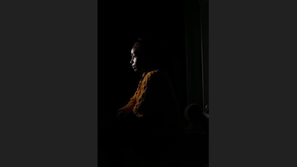 Headshot of a woman in an orange outfit inside a room with minimal light - Headshot photos, Charlotte portrait photographer